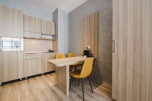 A modern kitchen with wooden cabinets, a built-in microwave, and a dining area with a wooden table and yellow chairs. - А17 Plovdiv Apartments Next to RowingChannel app7 (Plovdiv)