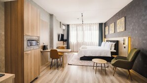 Une chambre d’hôtel moderne, équipée d’une armoire en bois, d’un lit, d’un bureau et d’une chaise.