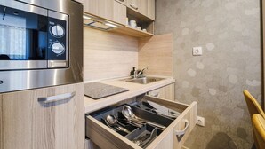 Une cuisine compacte équipée d’un four à micro-ondes encastré, d’un évier et d’un tiroir contenant des ustensiles.