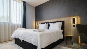 A modern bedroom with a large bed, a dark headboard, and a small table.