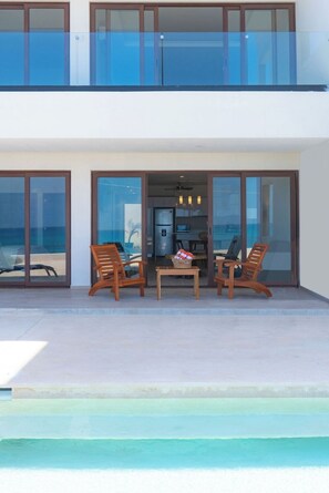 A modern two-story building with a balcony, large glass doors, and a pool. - Ocean Heaven: New Downtown Condo (Isla Mujeres)