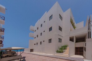 Ein modernes Gebäude mit markantem, winkelförmigem Design, mehreren Balkonen und blauem Himmel.