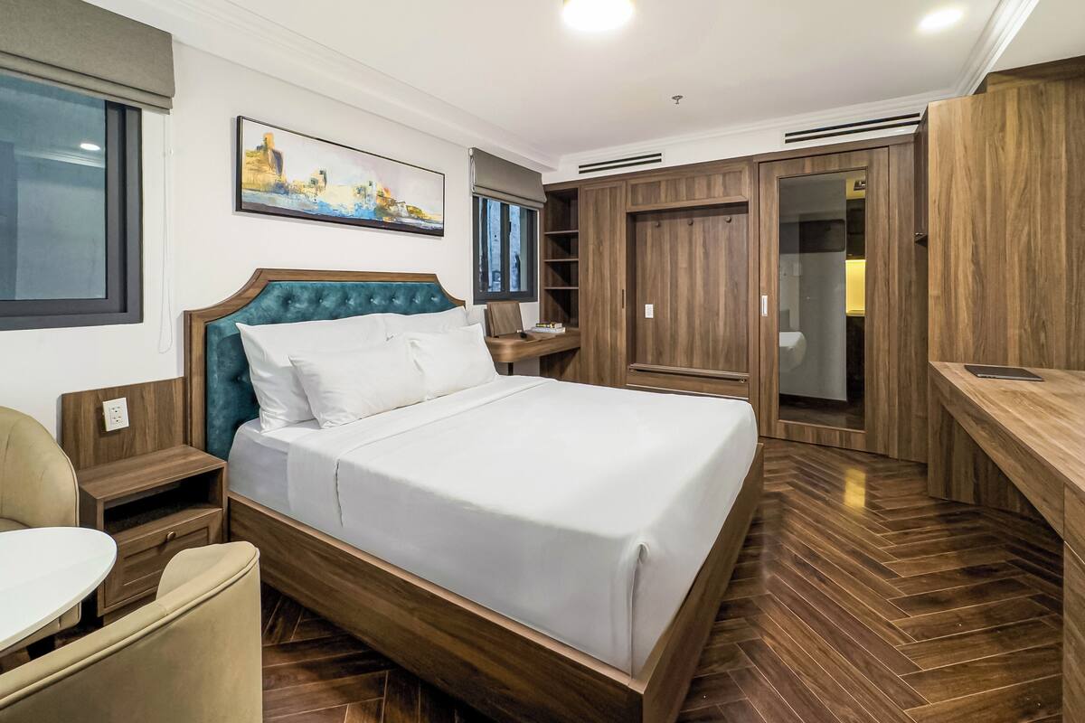 Ein modernes Hotelzimmer mit einem großen Bett, einem Holzschrank und einem Schreibtisch.