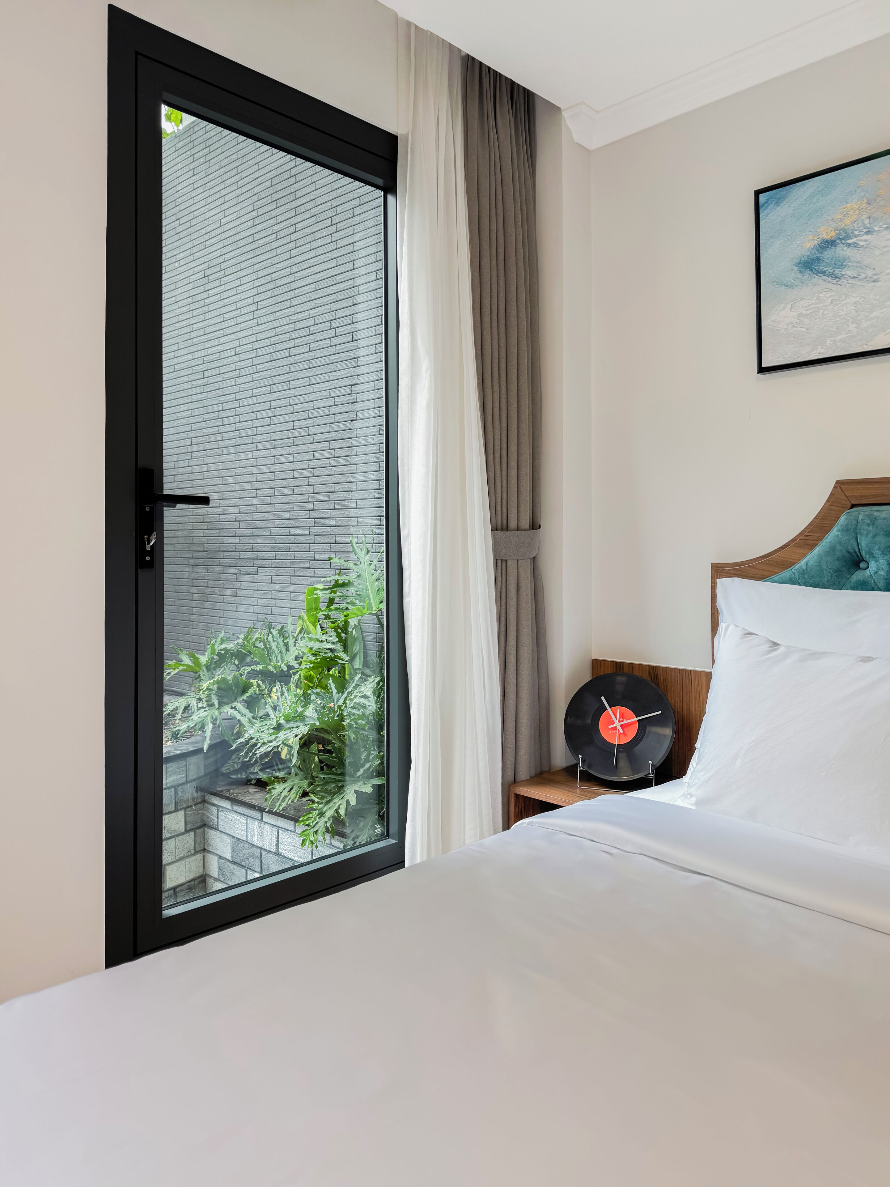 Habitación de hotel con cama, tocadiscos y vista a un edificio de ladrillo a través de una puerta de cristal.