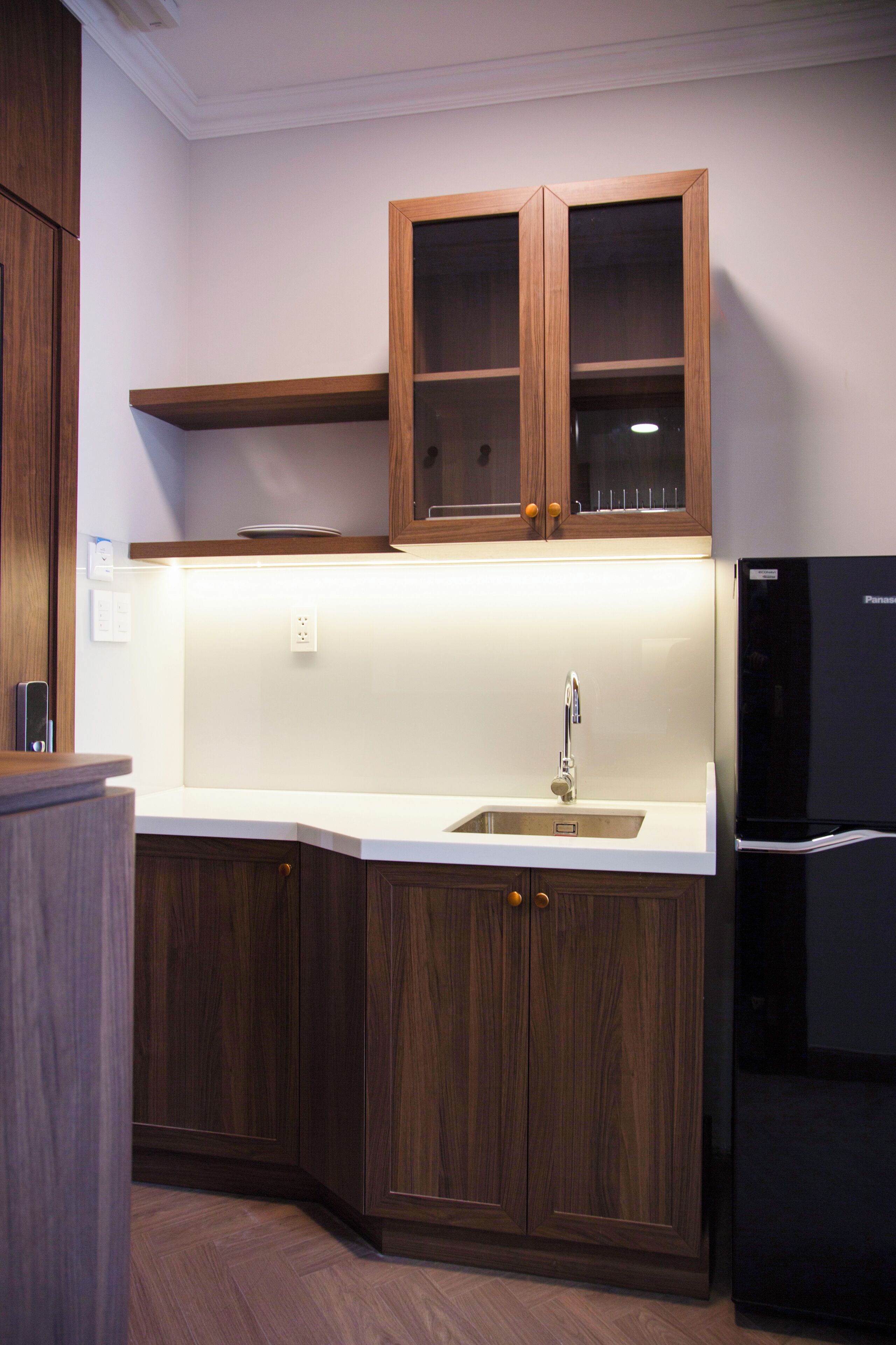 A kitchen with wooden cabinets, a black refrigerator, and a white countertop.