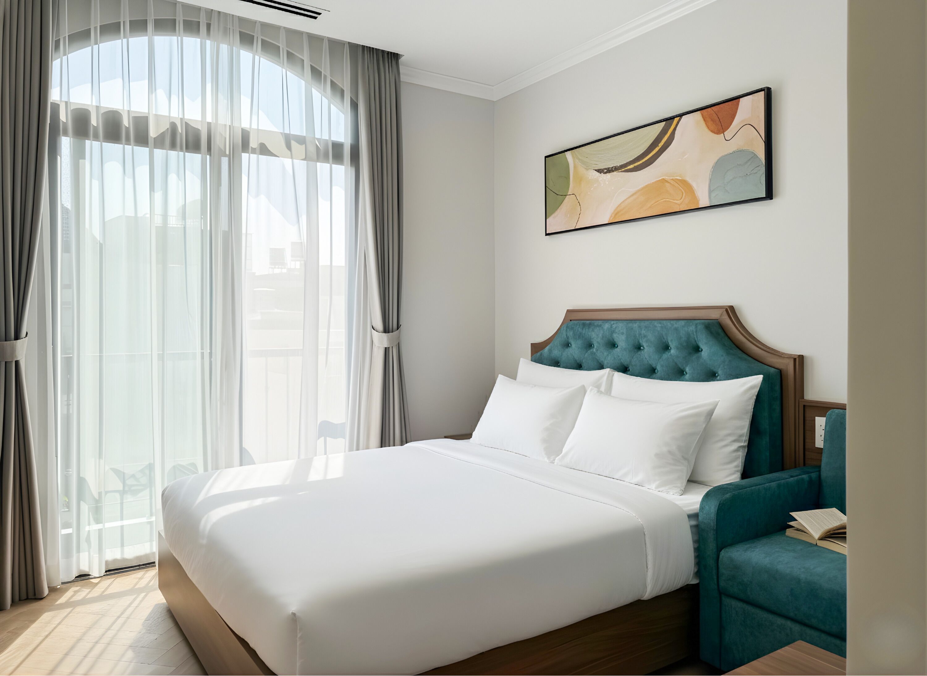 Ein Hotelzimmer mit einem großen Bett, einem smaragdgrünen Polsterkorb und einem modernen abstrakten Gemälde an der Wand.
