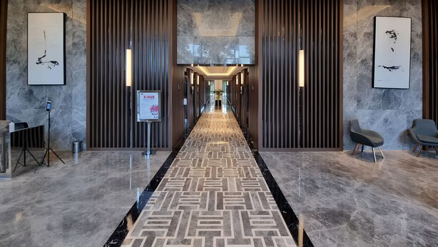 A modern hotel lobby with a geometric patterned carpet, marble flooring, and contemporary wall art. - Hava By SanLiving - 1 BR - Taman Anggrek (Jakarta)