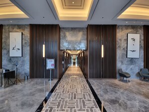 Eine moderne Hotelhalle mit einem geometrisch gemusterten Teppich, Marmorböden und zeitgenössischer Wandkunst.