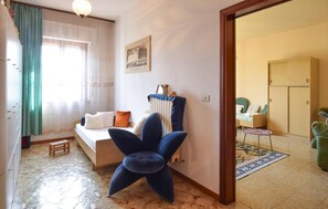 A cozy bedroom with a bed, a blue chair, a small table, and a wardrobe. - Beautiful home in Lari with outdoor swimming pool (Lari)