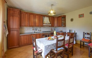 A kitchen with wooden cabinets, a dining table with chairs, and a hanging light fixture. - Gorgeous home in Lari with house a panoramic view (Lari)