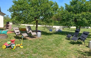 Un giardino con sedie a sdraio, un barbecue e un giocattolo per bambini.