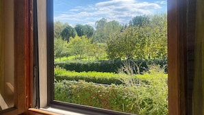 A window with a view of a well-maintained garden with various trees and hedges. - Beautiful home in Lari with outdoor swimming pool (Lari)