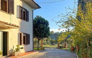 A paved pathway leading to a building with shutters and potted plants. - Gorgeous home in Lari with house a panoramic view (Lari)