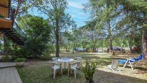 A patio with a table and chairs, surrounded by trees and a wooden deck. - Cozy apartment in Calci (Calci)