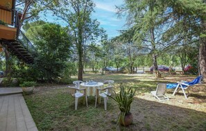 A patio with a table and chairs, surrounded by trees and a wooden deck. - Cozy apartment in Calci (Calci)
