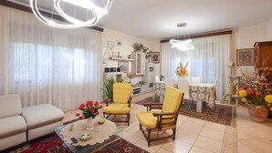 A living room with a sofa, two yellow armchairs, a coffee table with a vase of red flowers, a dining area with a table and chairs, and a chandelier. - Cozy apartment in Calci (Calci)