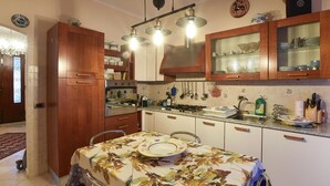 A kitchen with wooden cabinets, a stove, and a dining table set with plates. - Cozy apartment in Calci (Calci)