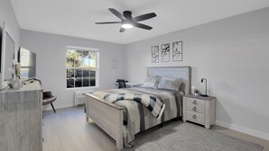 Een slaapkamer met een bed, nachtkastje en een plafondventilator.