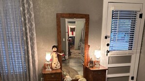 A bedroom with a bed, a dresser, a mirror, and a door with a window. - Charming 2-Bedroom House in the Heart of Round Top (Round Top)