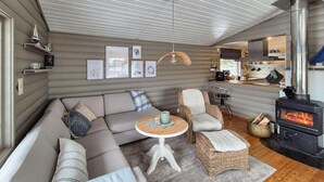 A cozy living room with a sectional sofa, wicker chairs, a small round table, and a wood-burning stove. - 3 bedroom beautiful home in Fjelberg (Fjelberg)