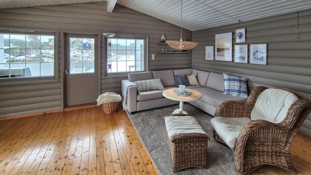 A cozy living room with a grey sofa, wicker chairs, a round coffee table, and a large window providing a view of the outside. - 3 bedroom beautiful home in Fjelberg (Fjelberg)