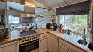 A compact kitchen with a gas stove, oven, and a coffee maker. There is a window with a view of trees and a built-in bench with cushions. - 3 bedroom beautiful home in Fjelberg (Fjelberg)