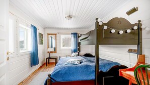 Una camera da letto con un letto a baldacchino, pavimento in legno, un tavolino e una sedia.