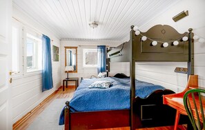 A bedroom with a four-poster bed, a wooden floor, a small table, and a chair. - Gorgeous home in Tretten with sauna (Tretten)