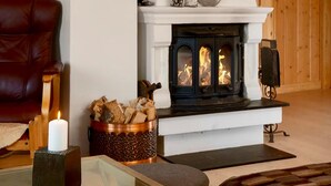 Un accogliente soggiorno con camino, una poltrona in pelle, una candela e un paiolo di legno.