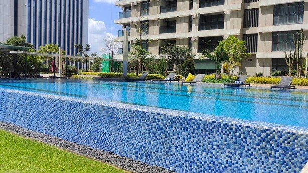 A swimming pool with blue mosaic tiles, surrounded by lounge chairs and greenery. - 1 Bedroom Furnished to let in GTC Westlands. (Nairobi)
