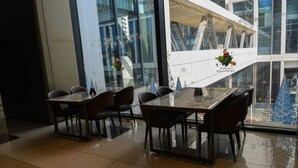 A modern dining area with a glass table and chairs, large windows, and a view of the city. - 1 Bedroom Furnished to let in GTC Westlands. (Nairobi)