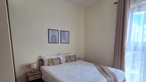 Una camera da letto ordinata con un letto grande, un comodino con una lampada e due quadri appesi al muro.