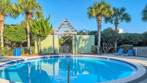 A circular pool with a wooden pergola structure in the background, surrounded by palm trees and a green wall. - Private Beach Access-Pool-Central Destin BP1003 (Destin)