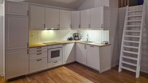 Una cocina compacta con gabinetes blancos, encimera de madera, horno empotrado y un lavamanos.