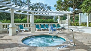 Un espace piscine doté d’un jacuzzi, de chaises longues et d’une pergola.
