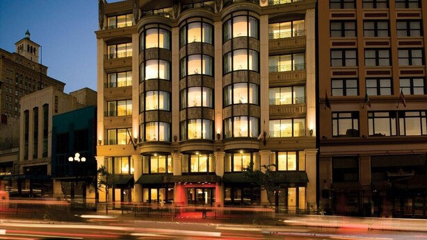 Een hotel met meerdere verdiepingen, met een klassiek ontwerp, grote ramen en een centrale ingang.
