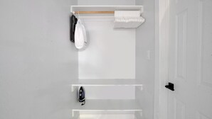 Ein schlichtes Badezimmer mit Handtuchhalter, einer aufhängbaren Tasche und einem Bügeleisen.