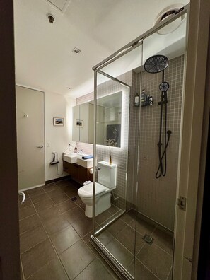 A bathroom with a glass-enclosed shower, a toilet, a sink, and a mirror. - Luxurious, modern, amongst it all (South Yarra)