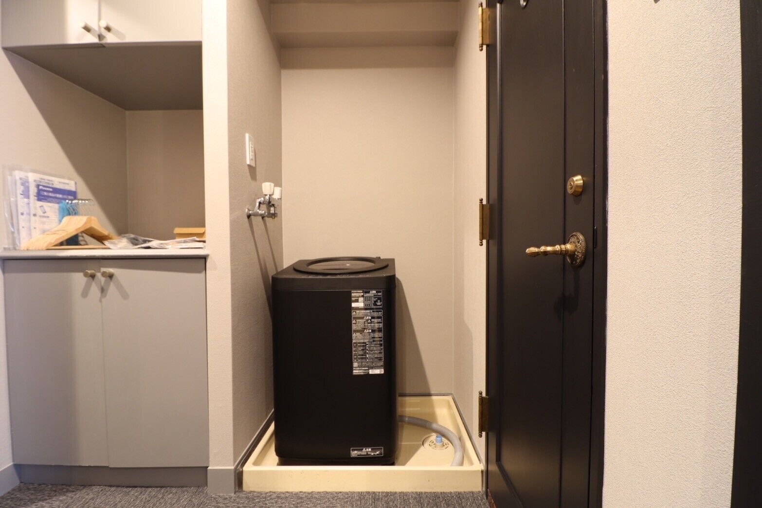 A compact room with a black heater, a white cabinet, and a door with a brass handle.