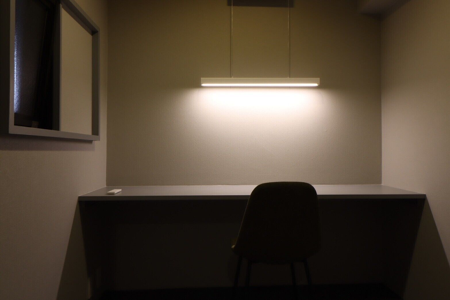 Une petite pièce faiblement éclairée, avec un bureau et une chaise.