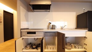 A modern kitchen with a built-in oven, microwave, and sink. There are cabinets with dishes and utensils stored inside.