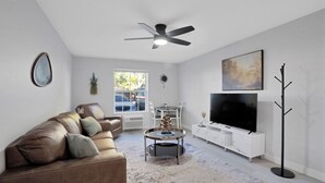 A modern living room with a leather sofa, a round coffee table, a flat-screen TV, and a ceiling fan. - Redspeck Luxury Furnished Flats (Aztec)