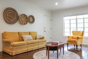 A living room with a sofa, armchair, coffee table, and decorative wall hangings. - Beautiful Riverfront Home on Medina River, sleeps 6 (Castroville)
