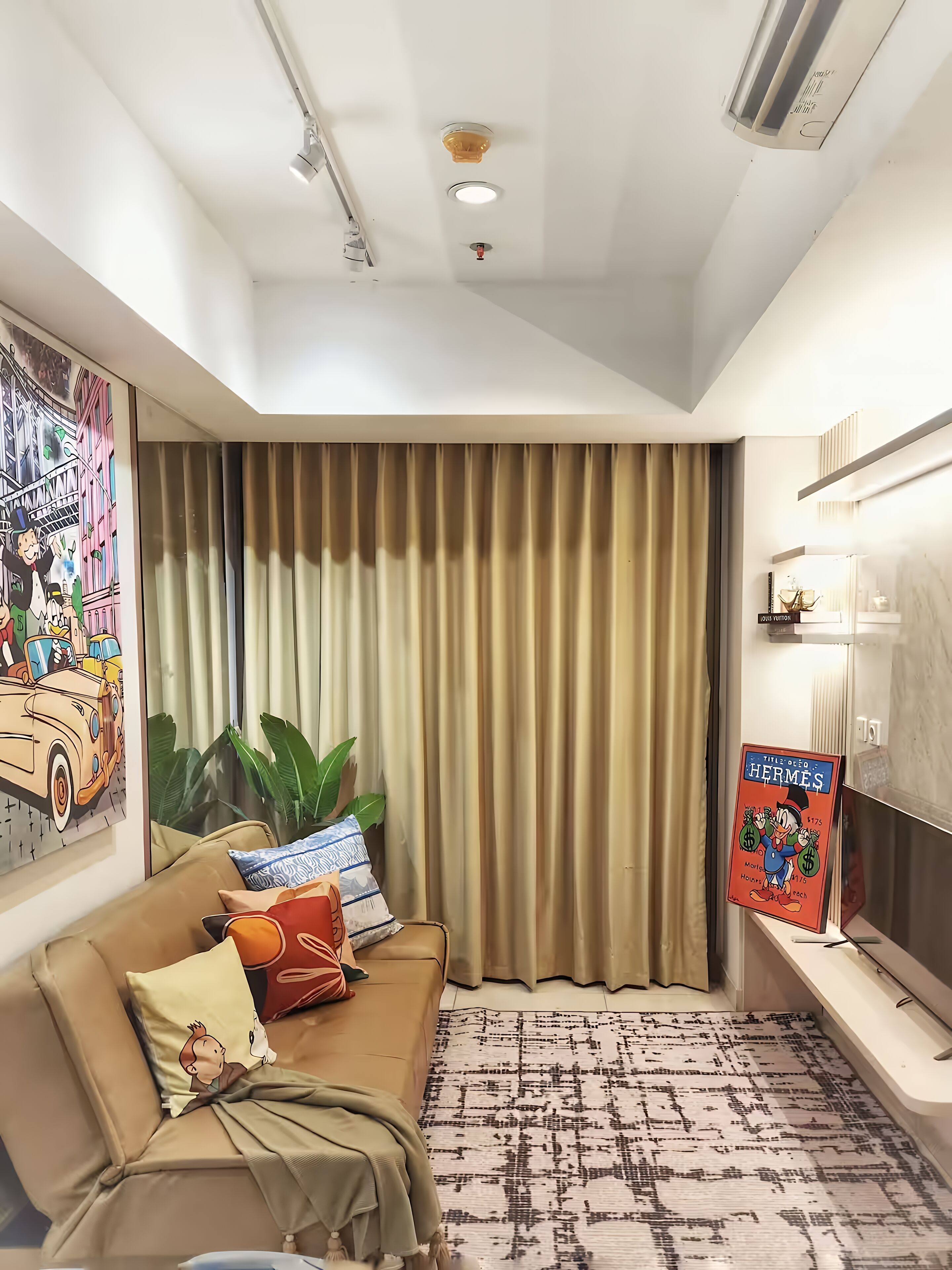 Una sala de estar moderna con un sofá color beige, alfombra estampada y un ventanal con cortinas.