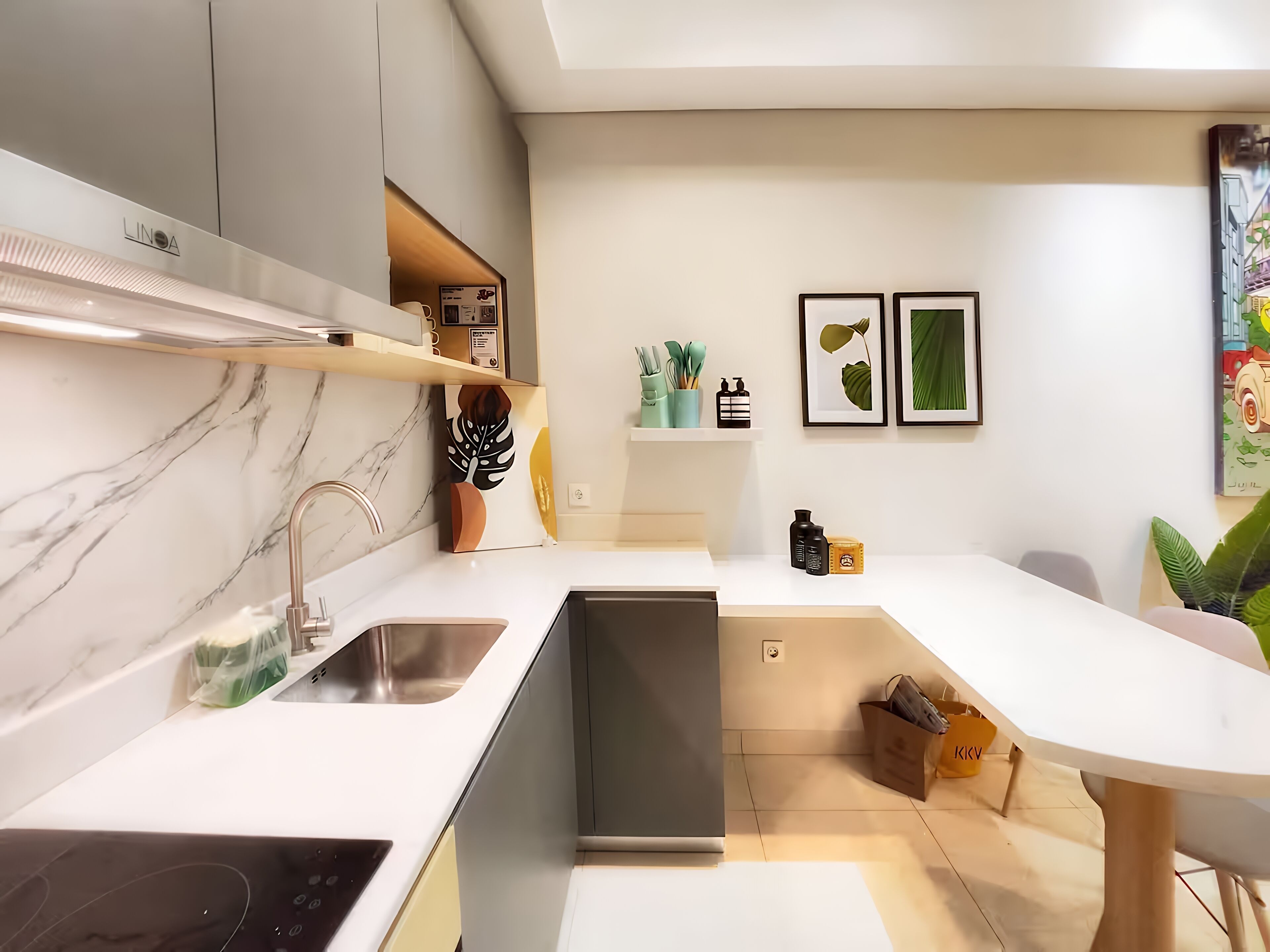 A modern kitchen with a built-in dishwasher, a sink, and a countertop. There are shelves with kitchen utensils and a small plant.