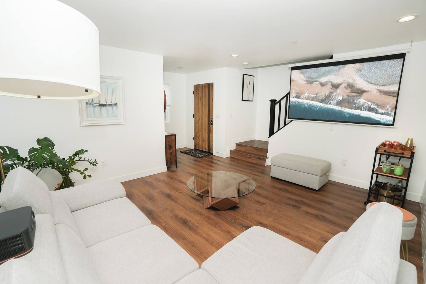 A modern living room with a sofa, a glass coffee table, and a staircase leading to another level.