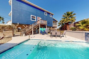 Une maison à deux étages avec une piscine, une terrasse en bois et un espace salon extérieur.