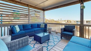 A covered outdoor seating area with wicker furniture and a view of the beach. - Private Pool, Large Back Porch, Golf Cart Access (Port Aransas)