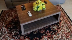 Un salon avec un canapé marron, une table basse en bois et un arrangement floral comme pièce maîtresse.