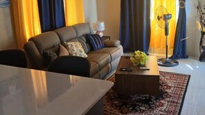 Un salon avec un canapé, une table basse et un ventilateur de plafond.